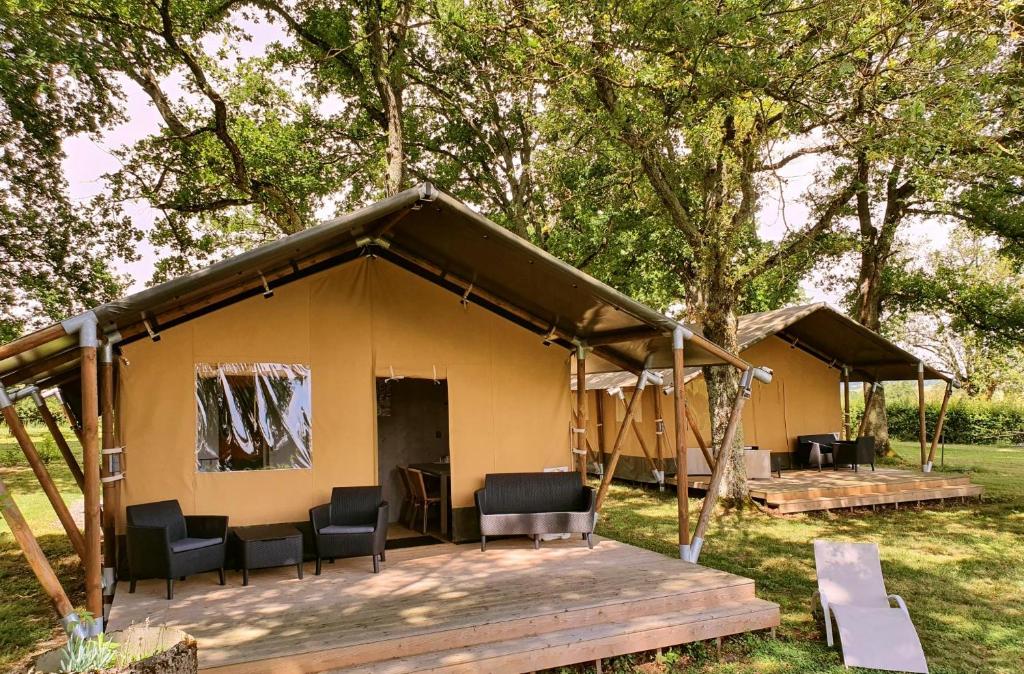 Tienda de campaña amarilla grande con sillas y porche en Glamping Les Arbres, Luxe Safaritent met zwembad, en Cronat