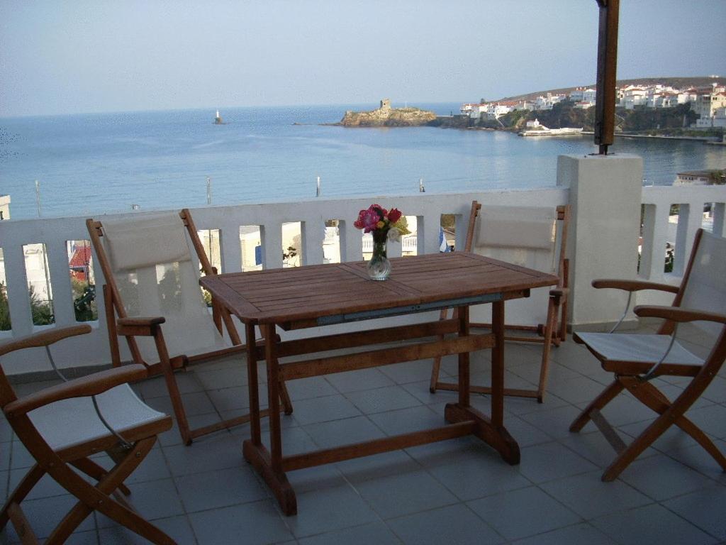 a wooden table on a balcony with a view of the ocean at Vassiliki Studios in Andros