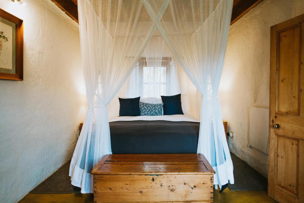 a bedroom with a canopy bed with a window at Beaumont Family Wines in Botrivier