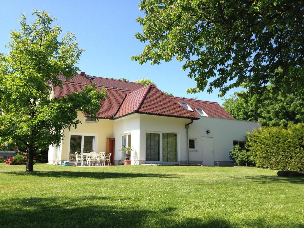 ein weißes Haus mit einem roten Dach und einem Hof in der Unterkunft Ferienhaus Am Park Leipzig in Leipzig