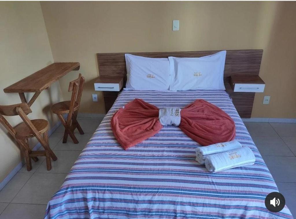 a bed with two clothes and a bow tie on it at Pousada Simão in Maragogi