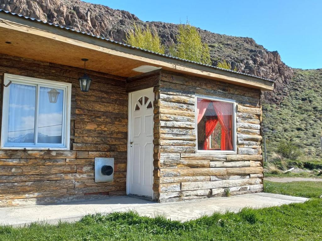 Cabaña de madera con puerta blanca y ventana en Complejo Las Maras II en El Chaltén