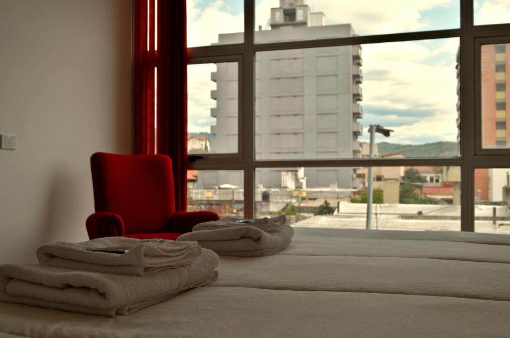 um quarto com uma cama com uma cadeira vermelha e uma janela em Parque Hotel em San Salvador de Jujuy