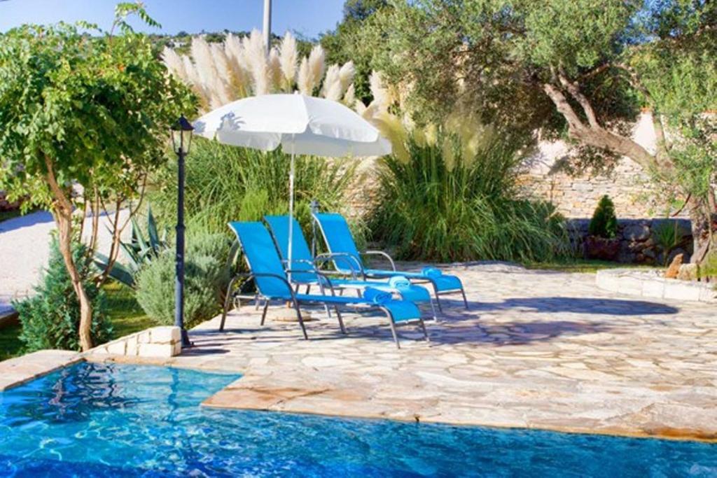 a group of chairs and an umbrella next to a pool at Villa Sonnhaus in Marina