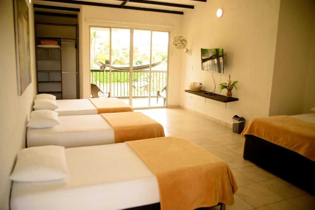 a hotel room with four beds and a balcony at Finca Hotel Loma Verde in Quimbaya
