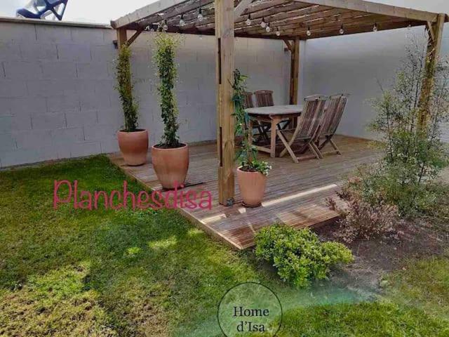 une terrasse en bois avec des plantes en pot et une table dans l'établissement Planchesdisa, à Saint-Pair-sur-Mer