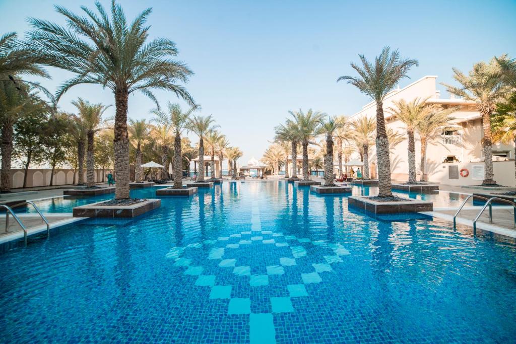 a swimming pool with palm trees in a resort at 1-bedroom apartment with pool in Dubai