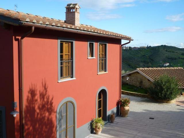 ein rotes Haus mit Topfpflanzen davor in der Unterkunft Agriturismo Casa Belvedere in Bacchereto