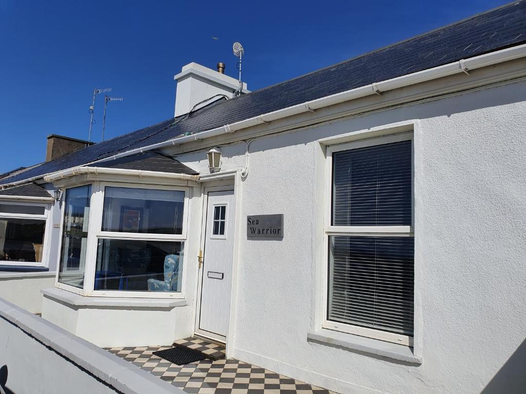a white house with a white door and windows at Sea Warrior Cottage in Kilkee