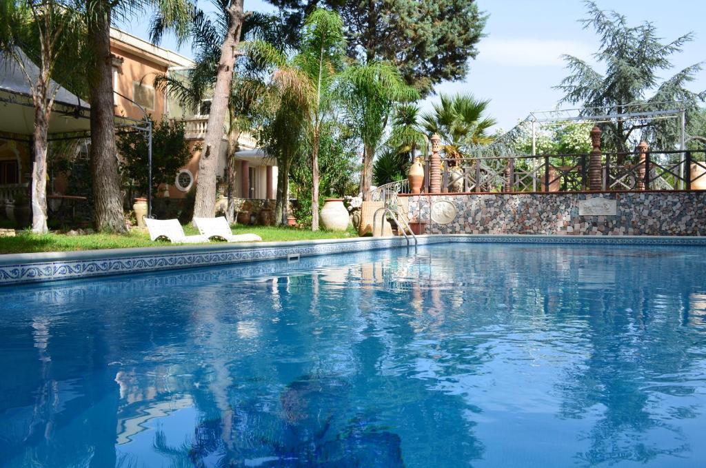 a large swimming pool with two white chairs in a yard at Villa Rubino in Catania