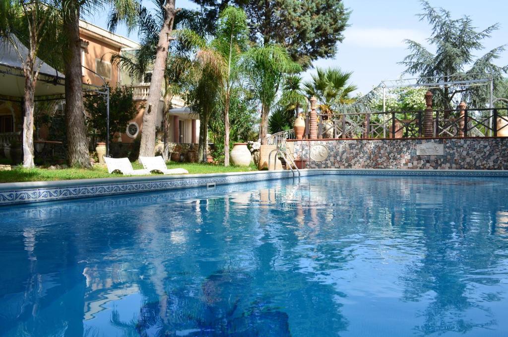 ein großer Pool mit zwei weißen Stühlen im Hof in der Unterkunft Villa Rubino in Catania
