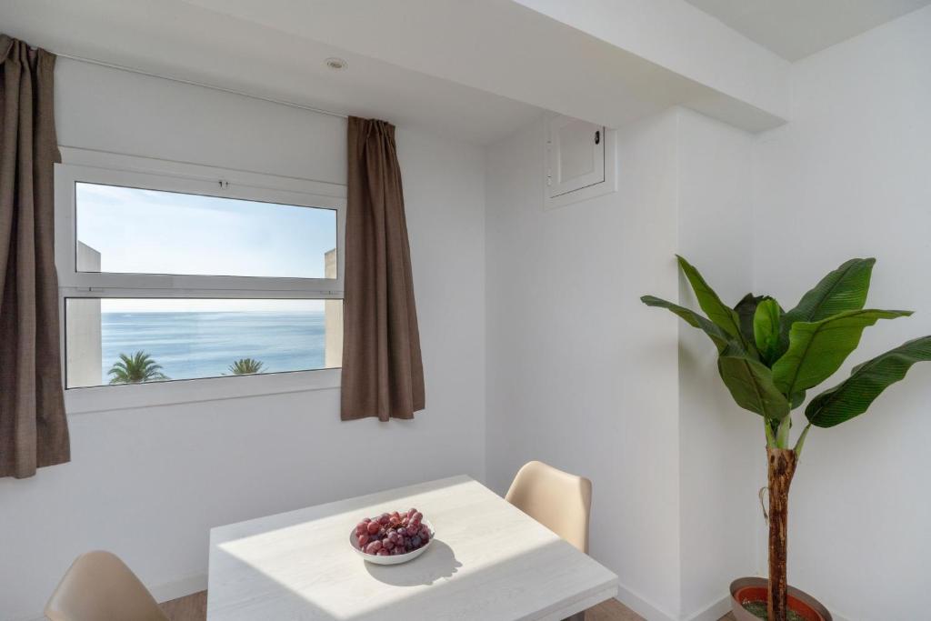 a white dining room with a table and a window at Apartamentos Venecia in Lloret de Mar