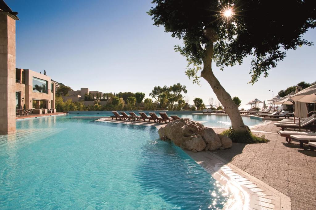 a swimming pool with lounge chairs and a tree at Rhodes Bay Hotel & Spa in Ixia