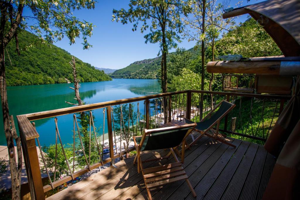 a deck with a chair and a view of a lake at Glamping Bagrem in Jablanica
