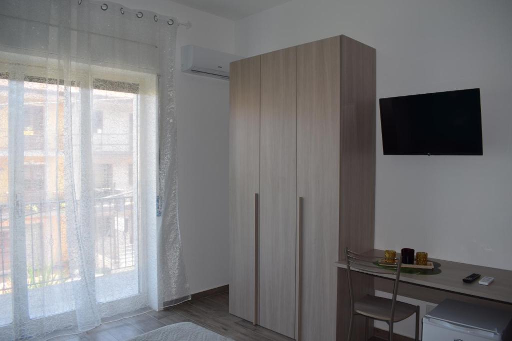 Zimmer mit einem Schreibtisch und einem Schrank mit einem TV in der Unterkunft Casa Ferrera - Locazione Turistica in Misterbianco
