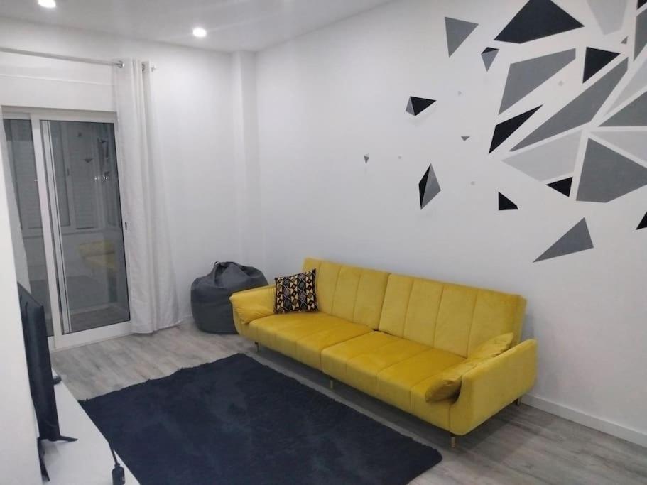 un sofá amarillo en una sala de estar con flechas negras en la pared en Lisbon, 3 bedroom apartment in Amora , 15 min from the beach en Amora