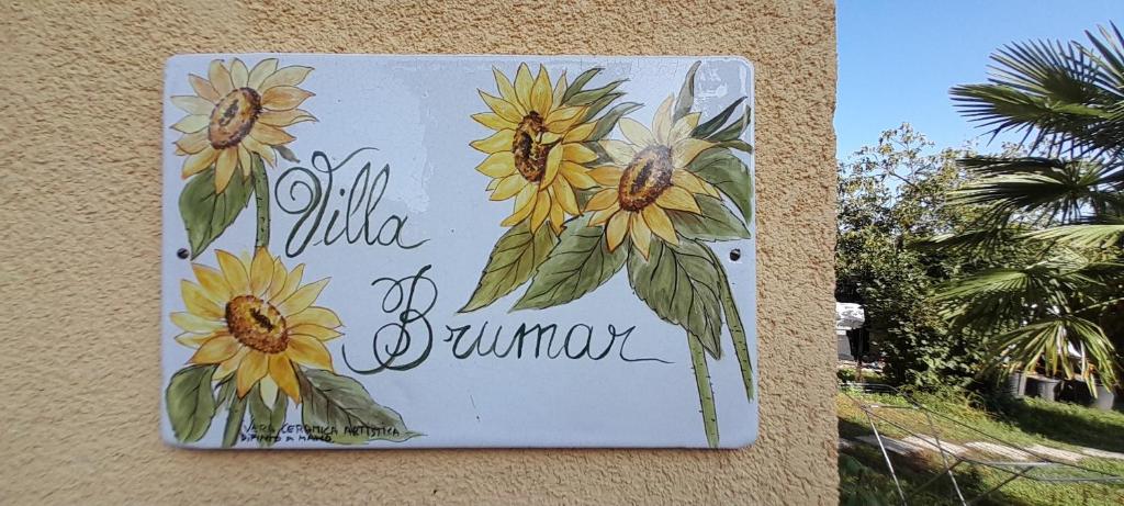 a sign on the side of a building with flowers on it at Villa Brumar in Brebbia