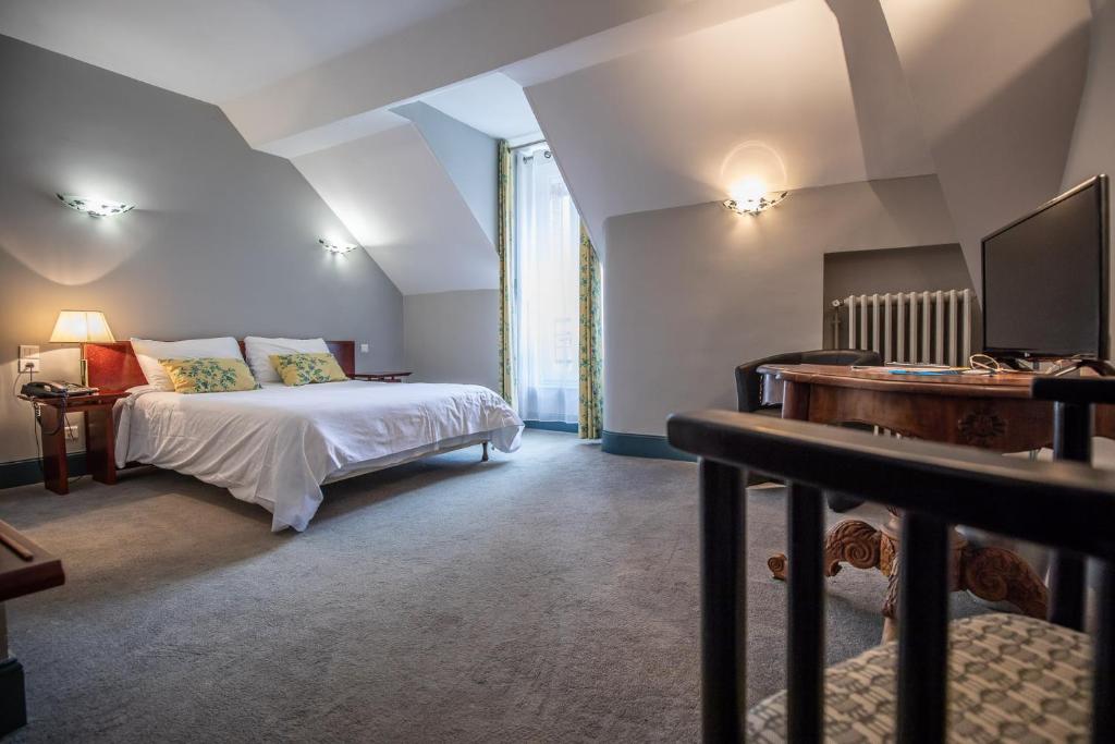 um quarto com uma cama, uma secretária e uma televisão em Hôtel Terminus em Cahors