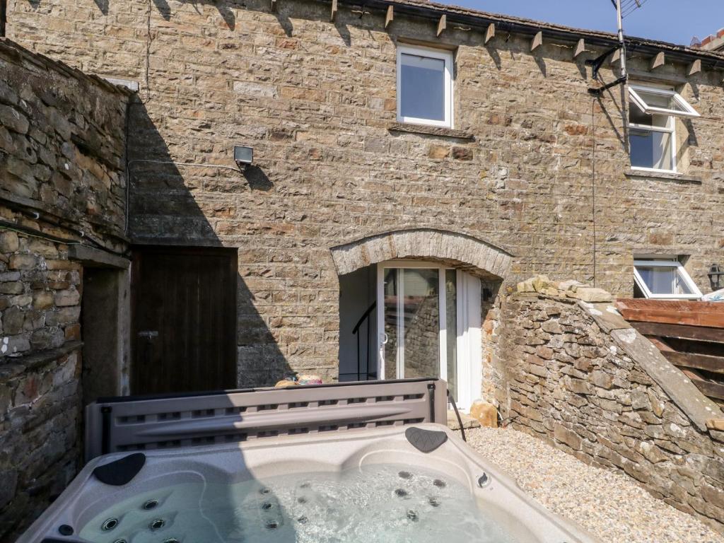 a stone house with a hot tub in front of it at Annabels Loft in Hawes