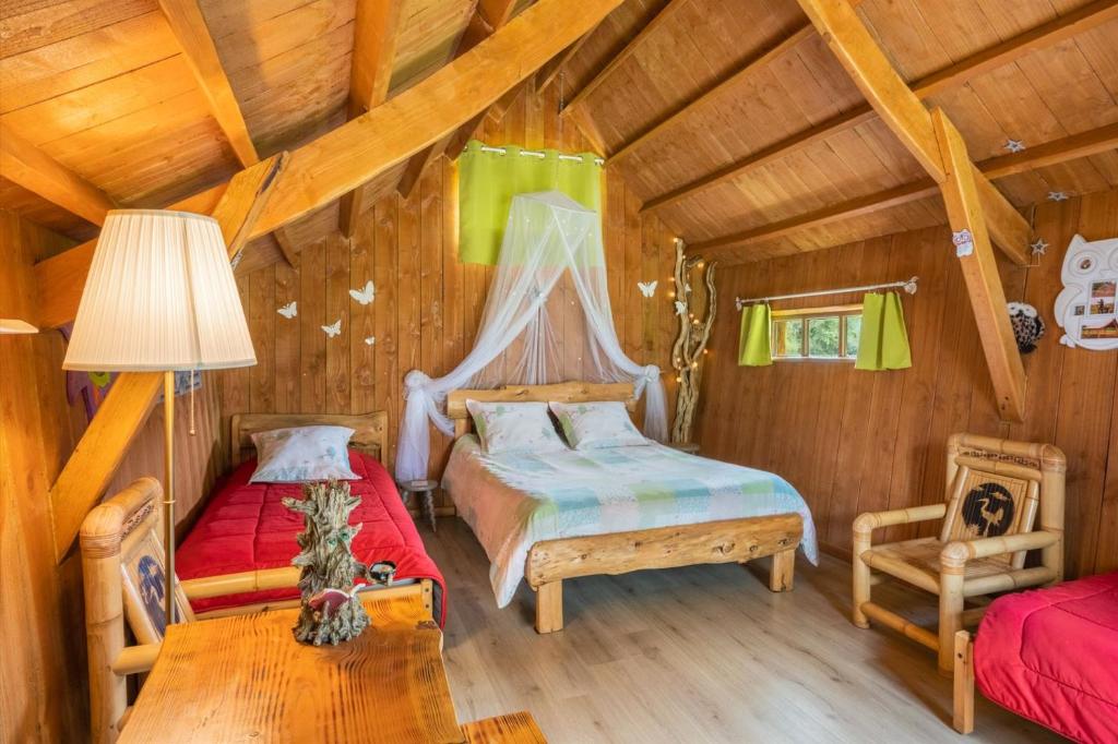 1 dormitorio con 2 camas en una cabaña de madera en La ferme de Piardiere, en Plessé
