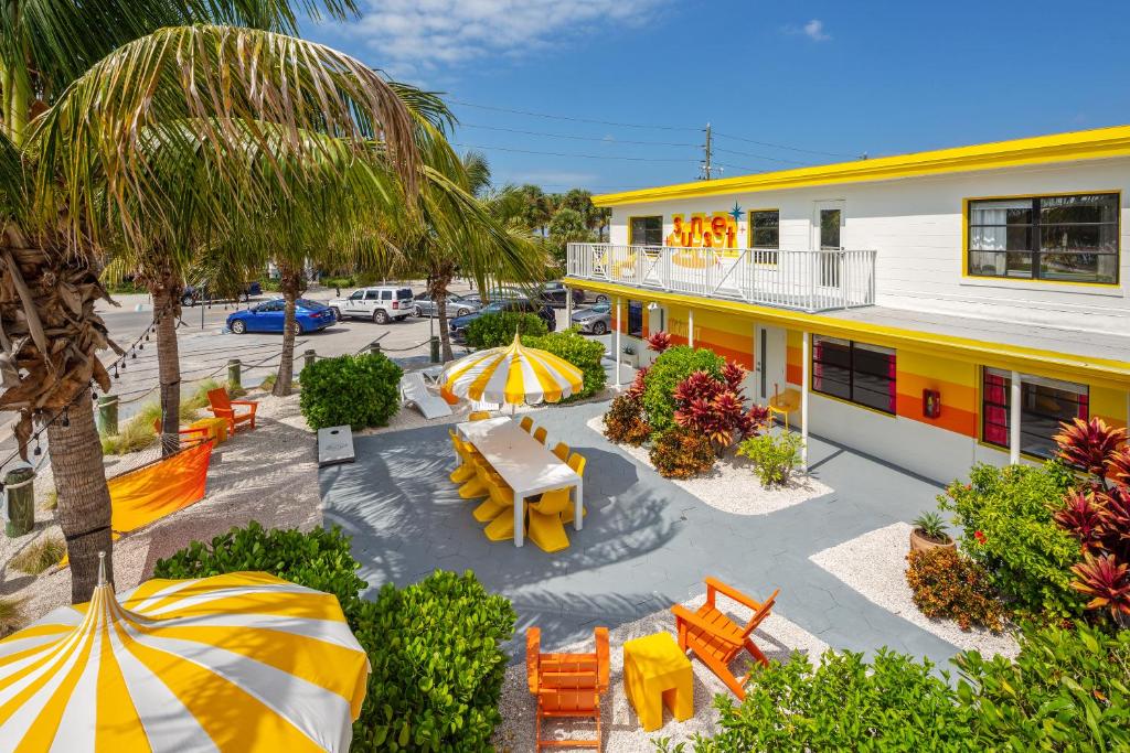 an outdoor patio with tables and umbrellas in front of a building at Sunset Inn and Cottages in St Pete Beach