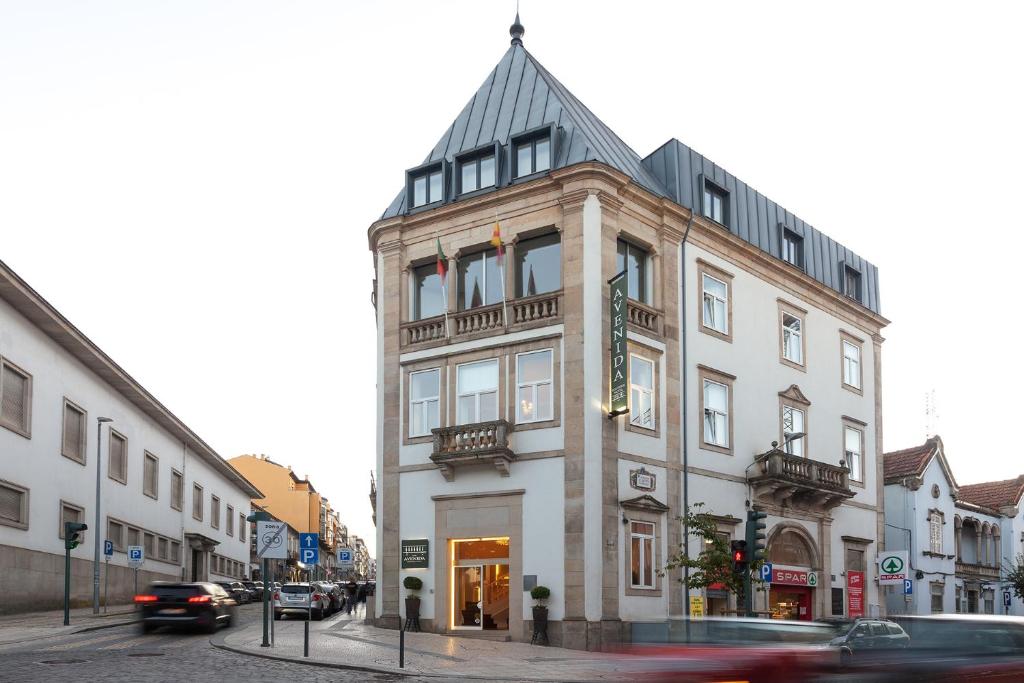 een hoog wit gebouw in een stadsstraat met auto's bij Avenida Boutique Hotel in Viseu