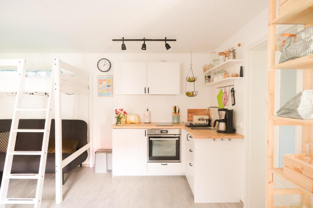 una piccola cucina con armadietti bianchi e una scala di Haus Hummel a Lieske