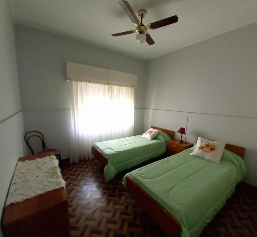 a bedroom with two beds and a ceiling fan at El Ceibo in Carhué