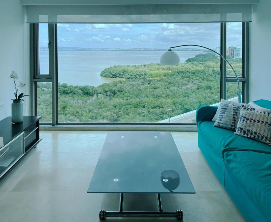 a living room with a blue couch and a large window at Luxury Apartment in Ocean Pavillion Hotel in Cartagena de Indias