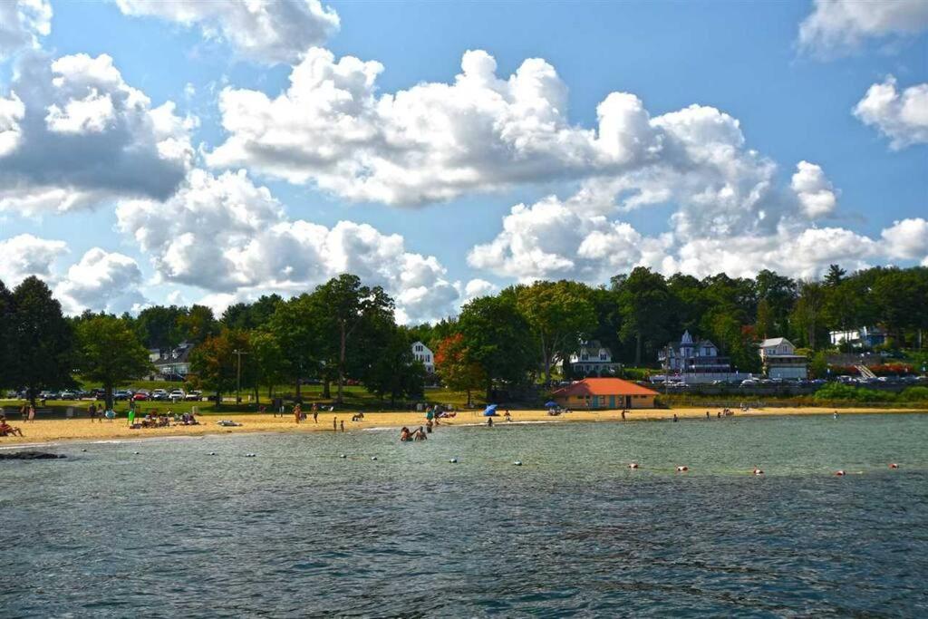 a beach with a group of people in the water at 2 Bdrm Condo walking distance to Weirs Beach in Laconia
