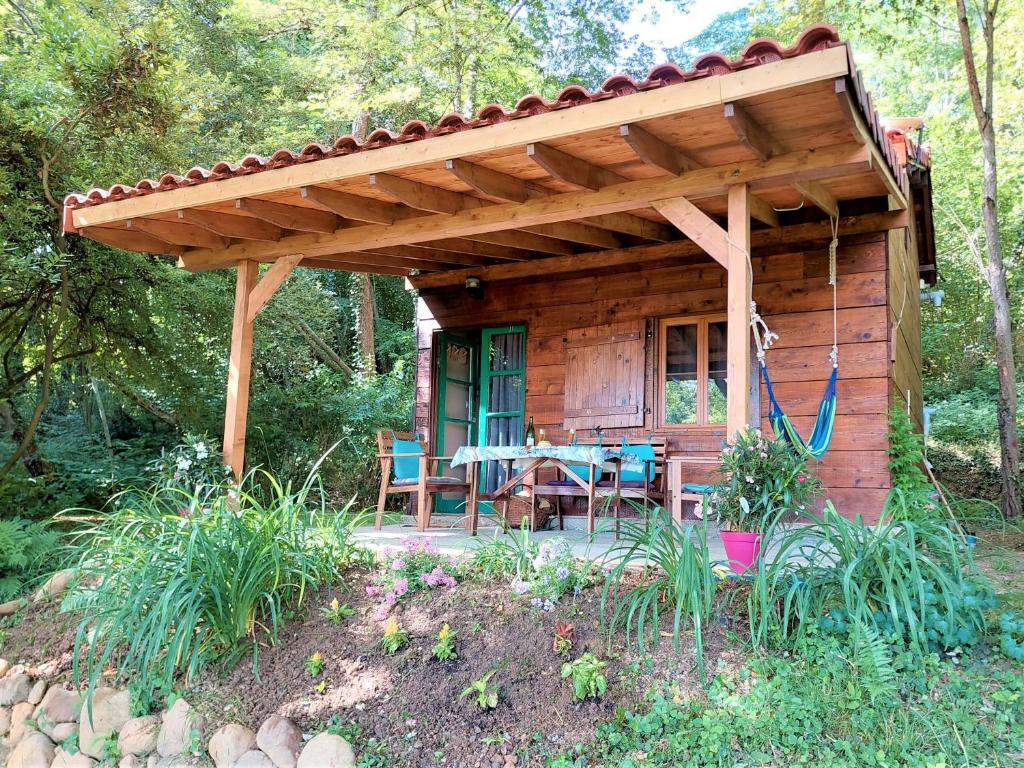 a wooden cabin with a table and a patio at Cabane dans les bois avec vue sur les Pyrénées in Saint-Laurent-de-Neste