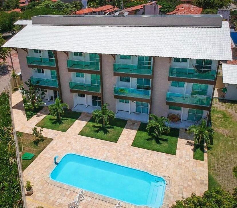 uma vista panorâmica de um edifício de apartamentos com uma piscina em Apartamento encantador térreo em condomínio fechad em Porto de Galinhas