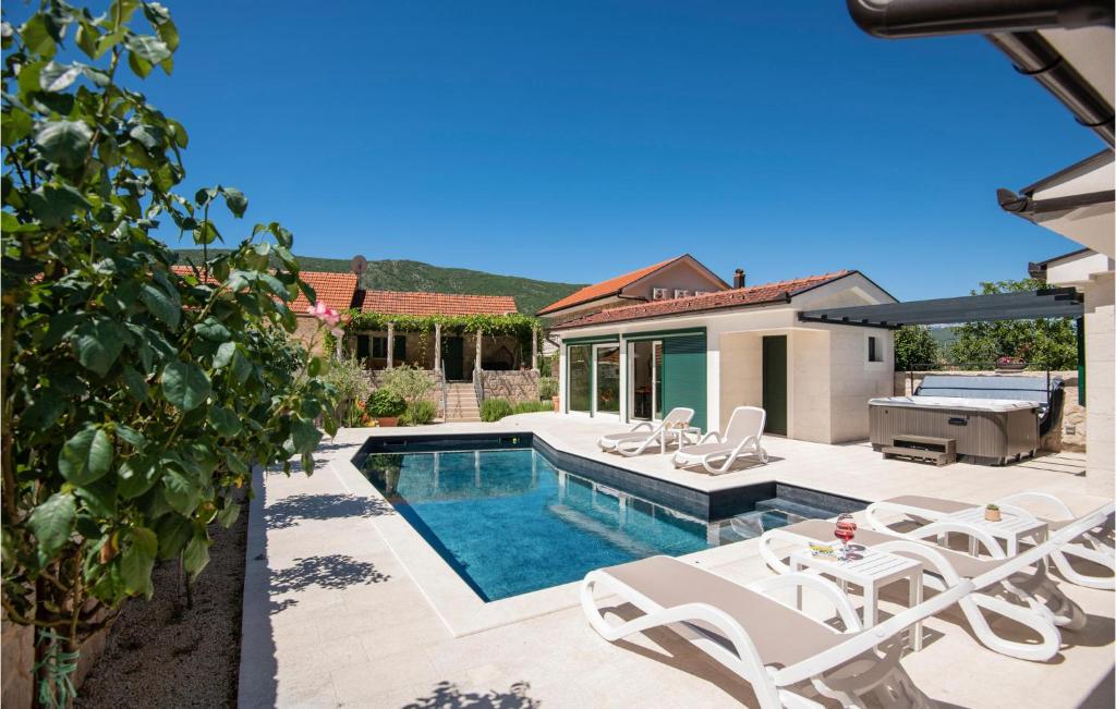 uma piscina com cadeiras brancas e uma casa em Gorgeous Home In Slivno With Heated Swimming Pool em Slivno