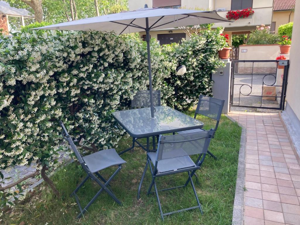 a table and chairs under an umbrella next to a hedge at Casa Luna - Airport in Pisa