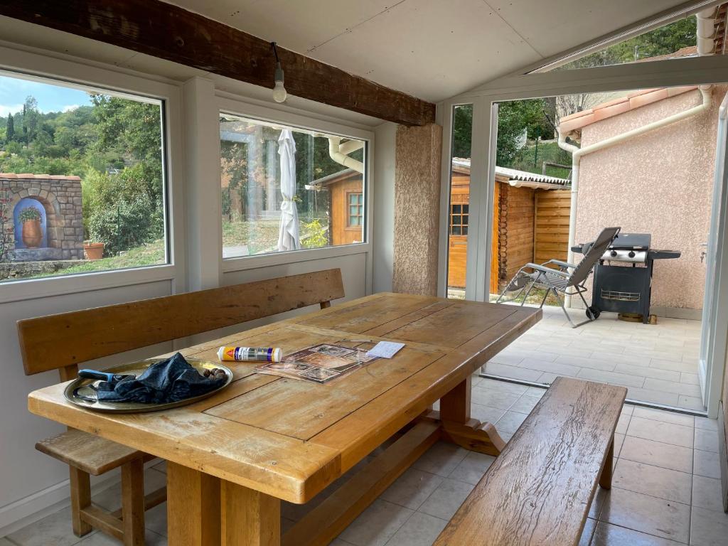 a wooden table in a room with two windows at Gîte ylangylang in Saint-Paul-le-Jeune