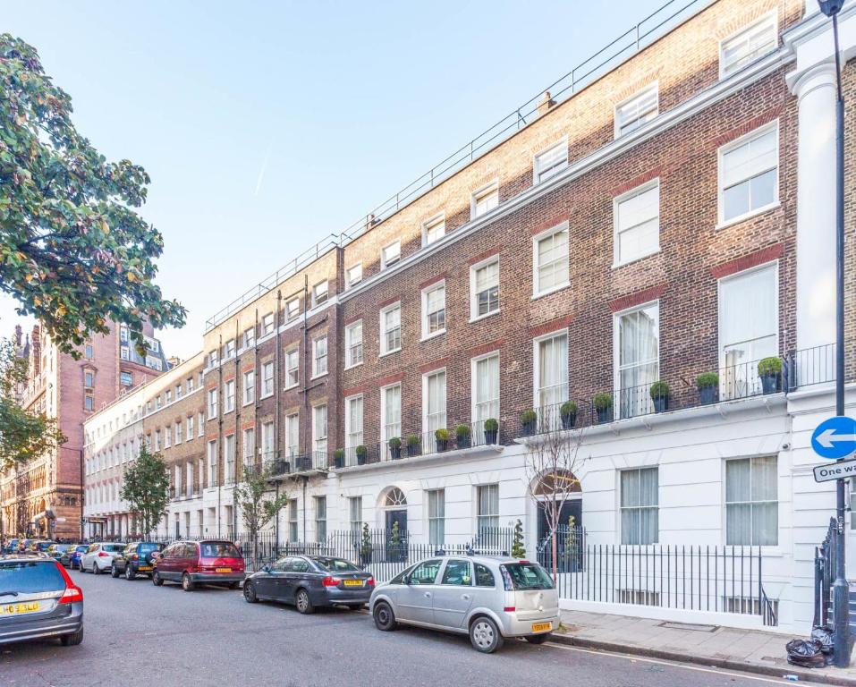 un gran edificio de ladrillo con coches estacionados frente a él en Cleveland Residences Russell Square en Londres