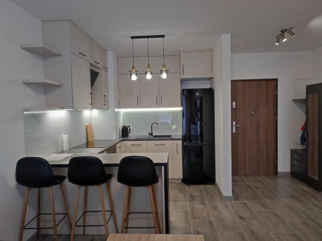 a kitchen with white cabinets and black appliances at Apartament Parkowa in Olecko