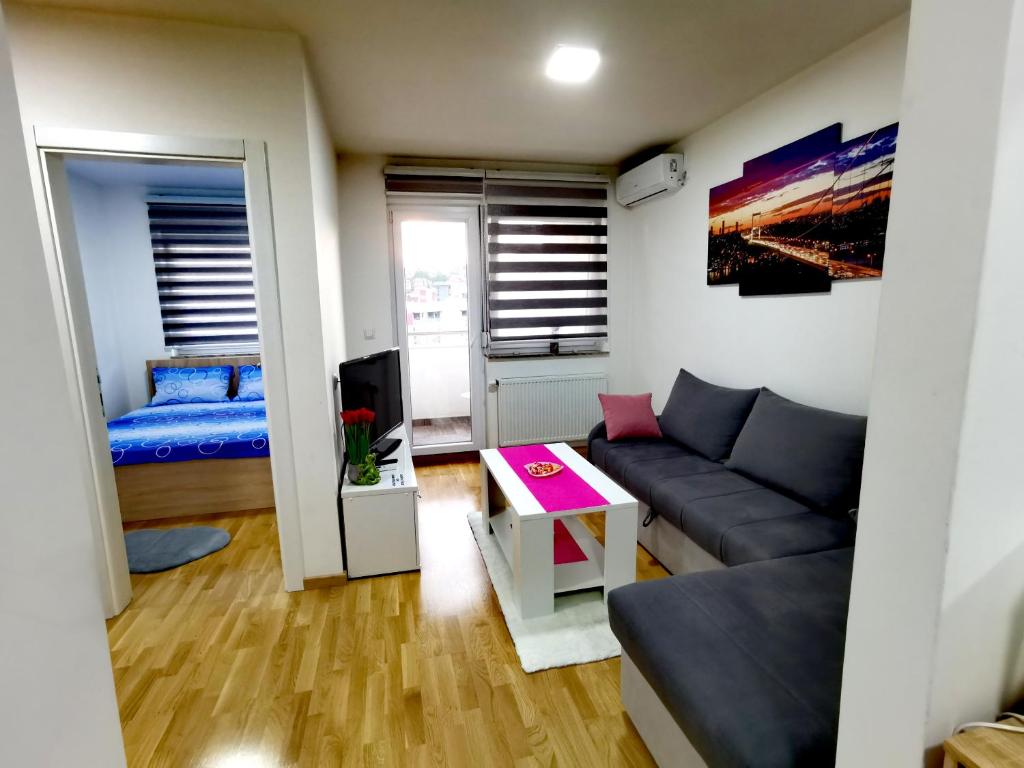 uma sala de estar com um sofá e uma cama em Apartman Lena em Doboj