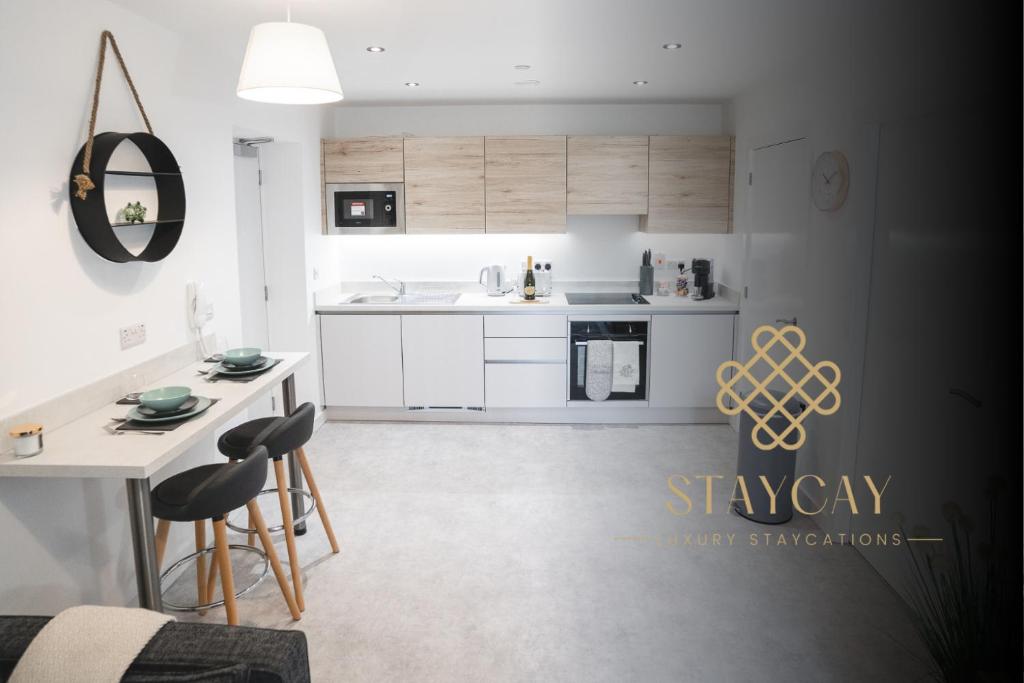 a kitchen with white cabinets and a table and chairs at Birtin Works Apartments - Brand New - City Centre in Sheffield