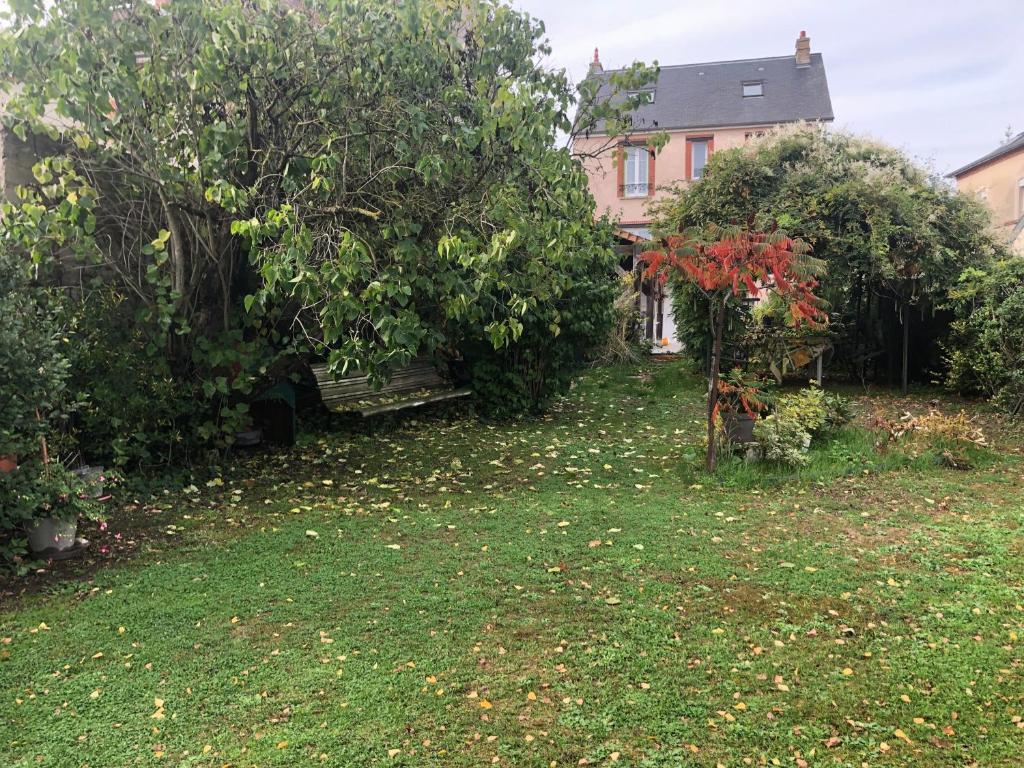 einen Hof mit Bäumen und Sträuchern und ein Haus in der Unterkunft Villa l'INSOUCIANCE en Champagne in Vincelles