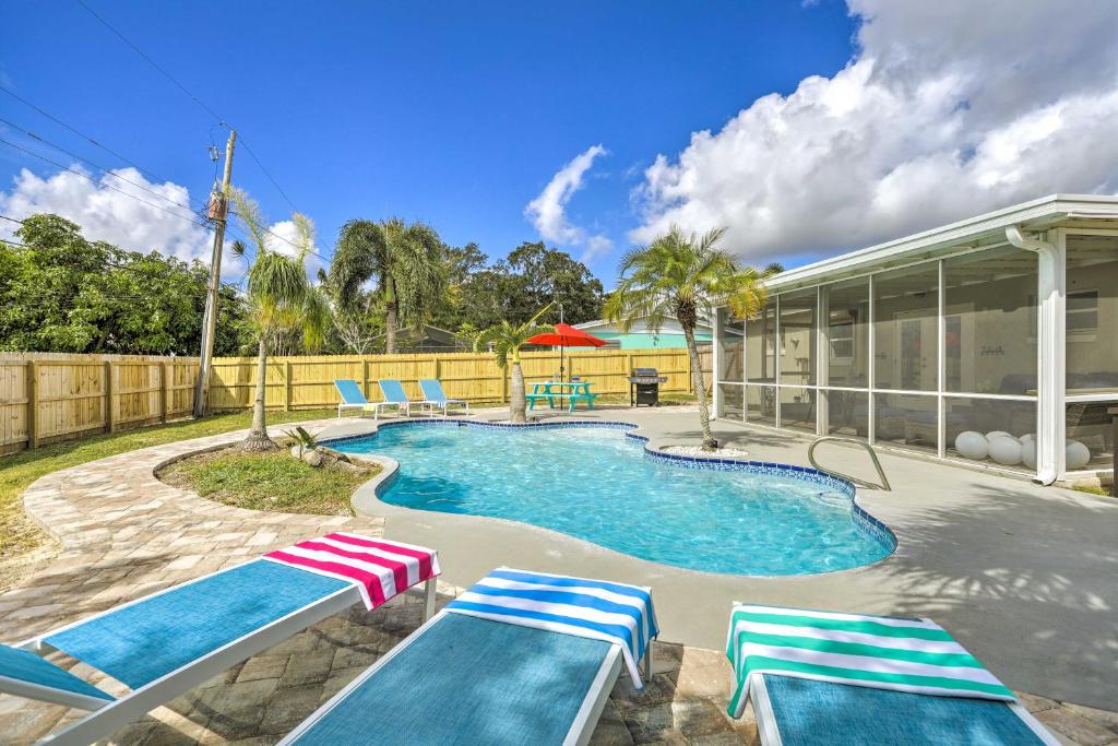 a swimming pool with lounge chairs next to a house at Merritt Island Oasis with Pool about 7 Mi to Beach! in Merritt Island