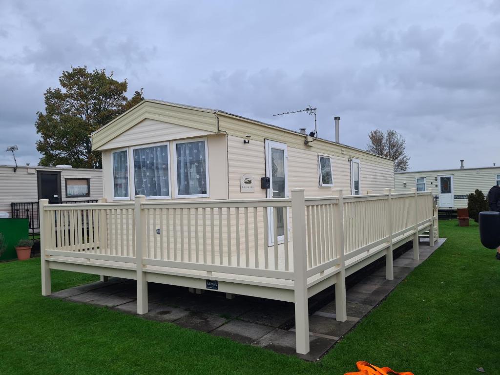 a white house with a porch and a deck at 6 berth 3 bedroom Northshore Skegness Emirates in Skegness