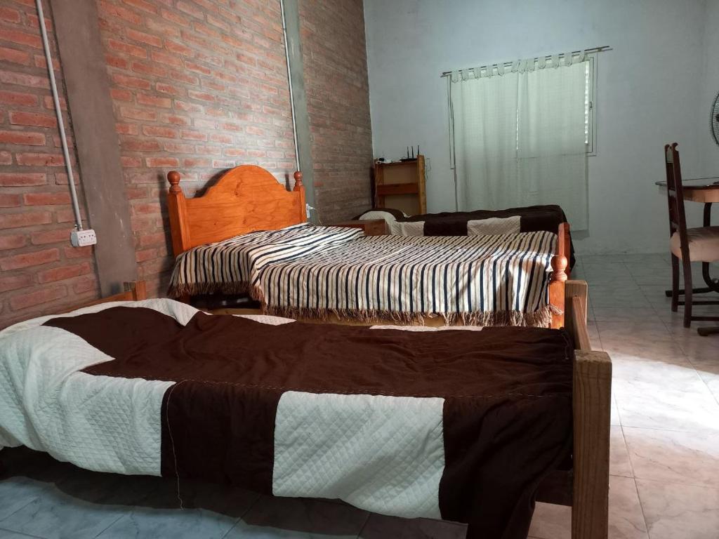 Dos camas en una habitación con una pared de ladrillo. en Depto Guemes, en San Luis