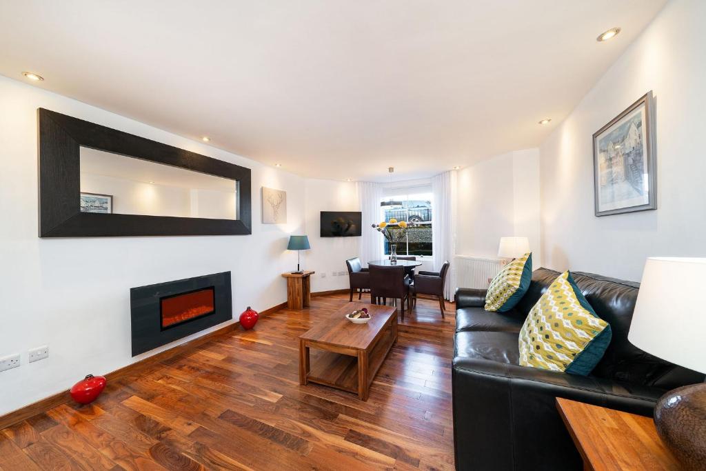 a living room with a black leather couch and a fireplace at The Shore Apartment in Queensferry