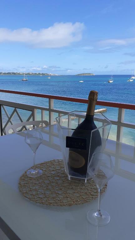 eine Flasche Wein auf einem Tisch mit zwei Gläsern in der Unterkunft Grand Studio « Blue Sunset » mer, plage, piscine. in Marigot