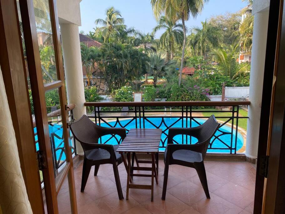 a balcony with a table and chairs and a pool at 2BHK Pool Facing Beachside Luxury Homestay In South Goa in Betalbatim