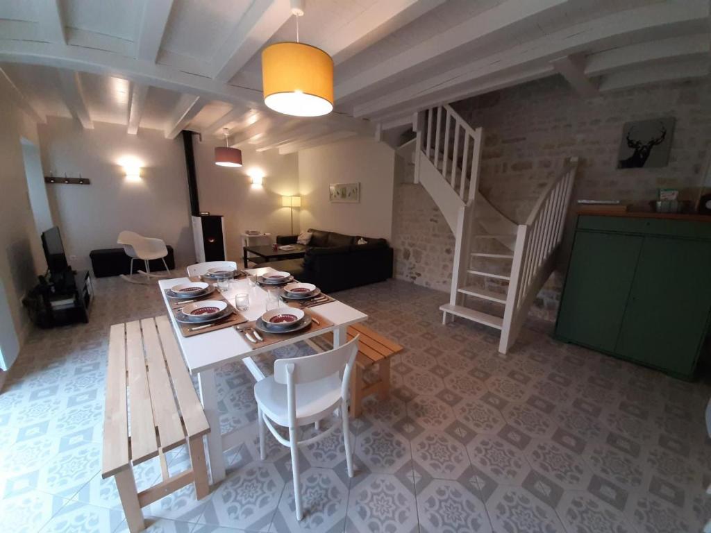ein Wohnzimmer mit einem Tisch, Stühlen und einer Treppe in der Unterkunft Gîte Coulonges, 4 pièces, 6 personnes - FR-1-653-127 in Coulonges