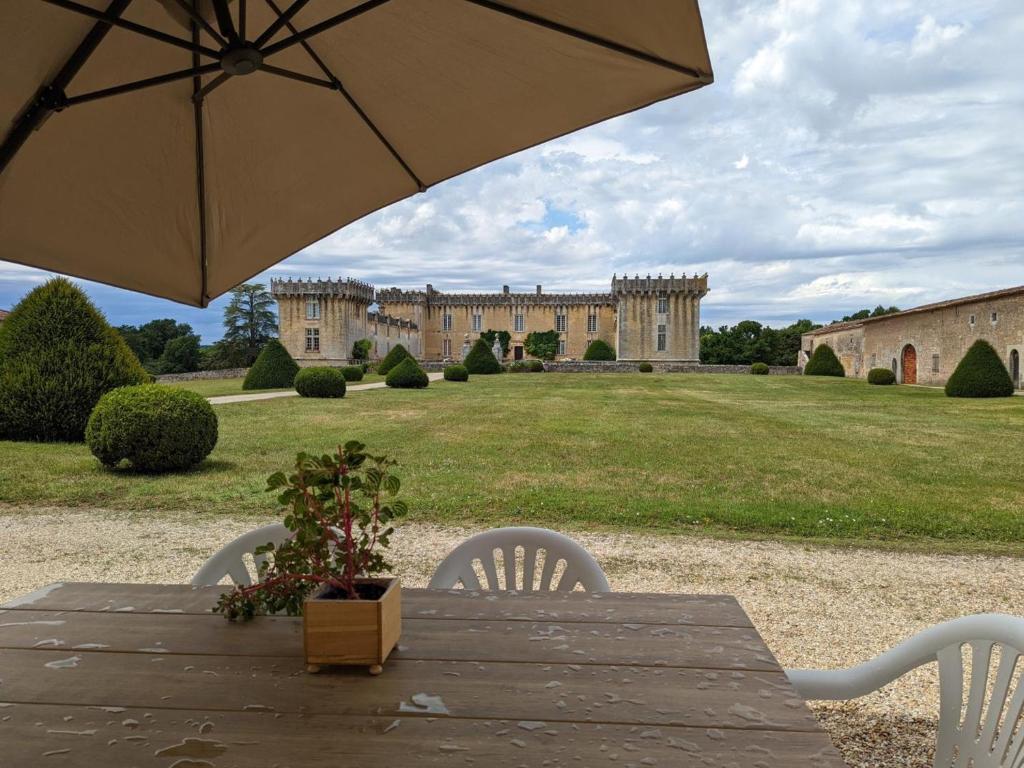 a table with an umbrella in front of a building at Gîte charmant au cœur d'un château historique avec parc, proche de Cognac, idéal famille et nature - FR-1-653-167 in Cherves-de-Cognac