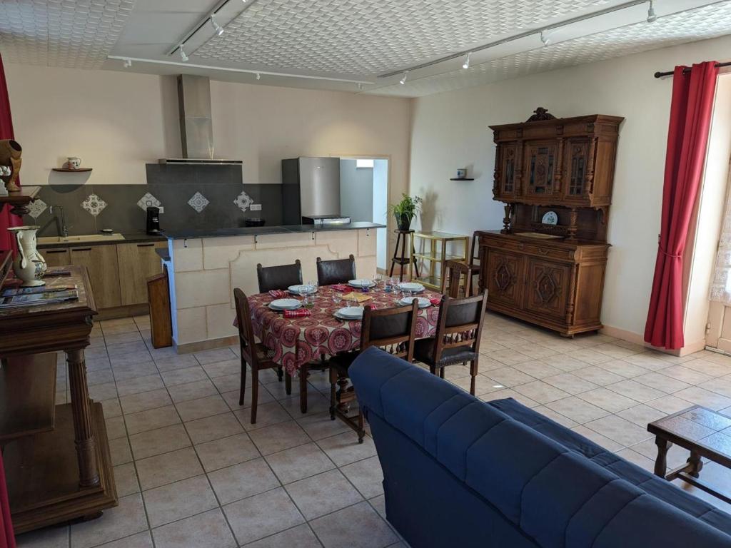a living room with a table and a kitchen with a blue couch at Gîte Cherves-Richemont, 3 pièces, 5 personnes - FR-1-653-205 in Cherves-de-Cognac