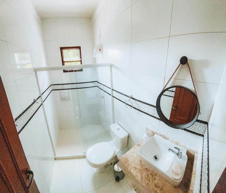 a white bathroom with a toilet and a sink at Pousada Carvalhos - Camaçari in Camaçari